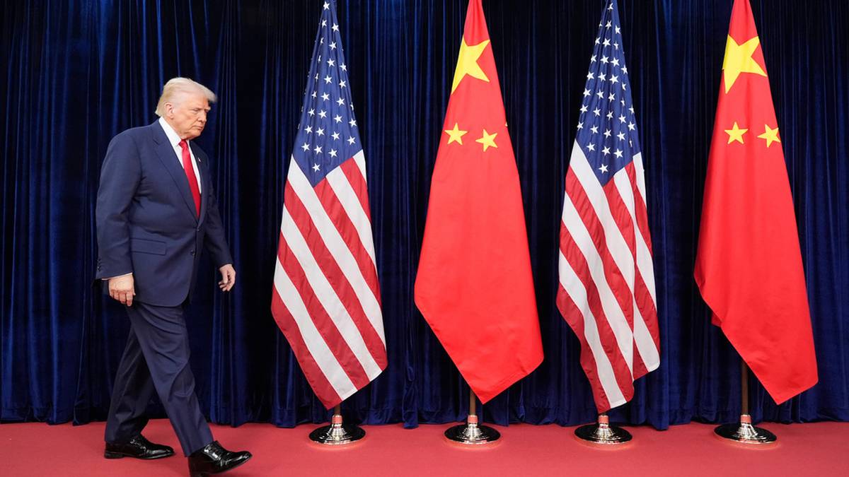 Donald Trump idzie obok flag Stan&oacute;w Zjednoczonych i Chin.