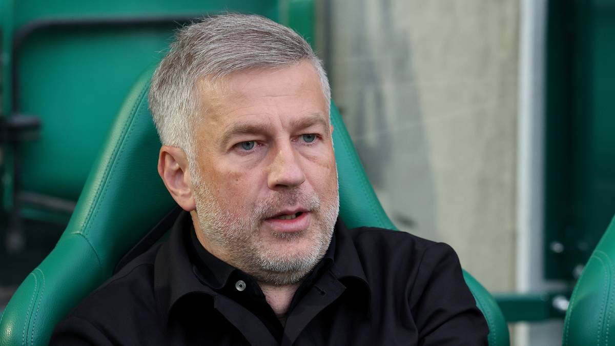 Portret mężczyzny z siwymi włosami i zarostem, siedzącego na zielonym krześle.