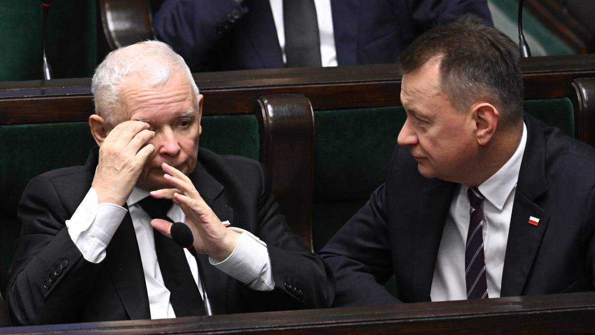 Dwóch polityków w garniturach siedzi w ławach sejmowych. Starszy mężczyzna z siwymi włosami przeciera oczy dłońmi, obok niego siedzi drugi mężczyzna.