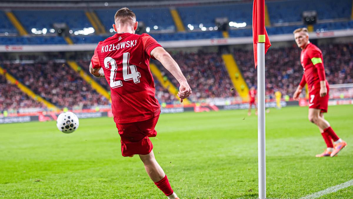 Piłkarz w czerwonej koszulce z numerem 24 kopie piłkę nożną, podczas meczu na stadionie.