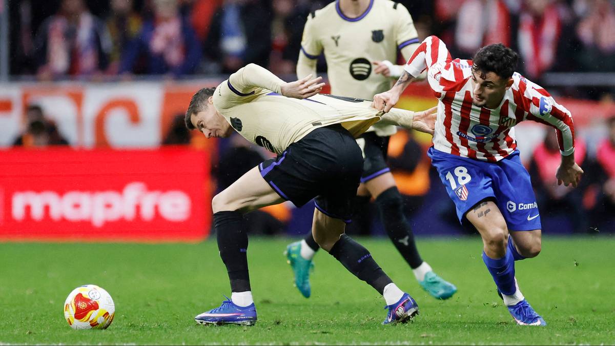 Piłkarze walczą o piłkę na murawie stadionu.